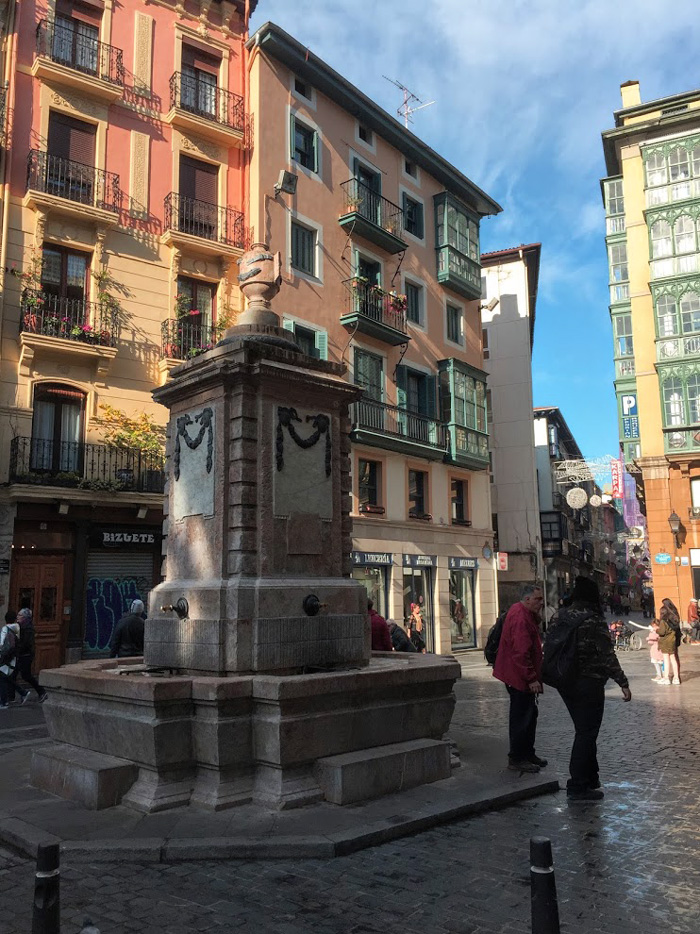 Bilbao Old Town with statue and couple walking away