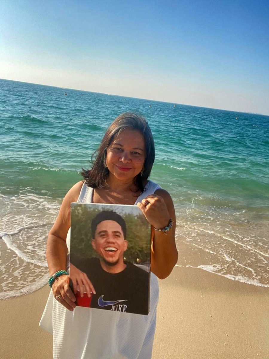 Stalked Into Fleeing America And Thriving Overseas 4 Mom at beach holding photo of son smiling. Stalked into fleeing America