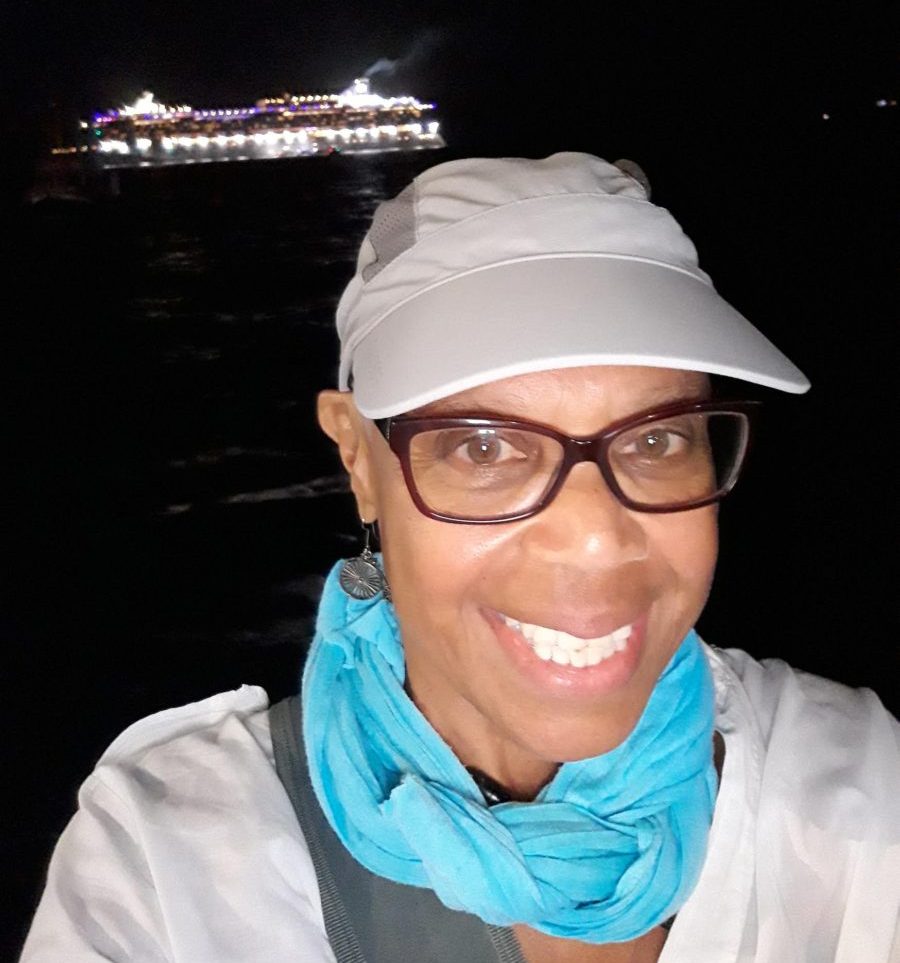 Maria Belton with ship in background cream hat black older woman