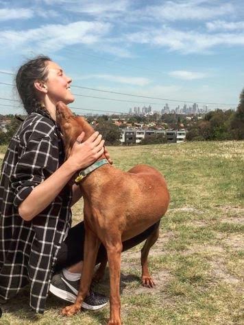 pet and house sitting world travels, woman with brown lab in an opne field with city skyline behind